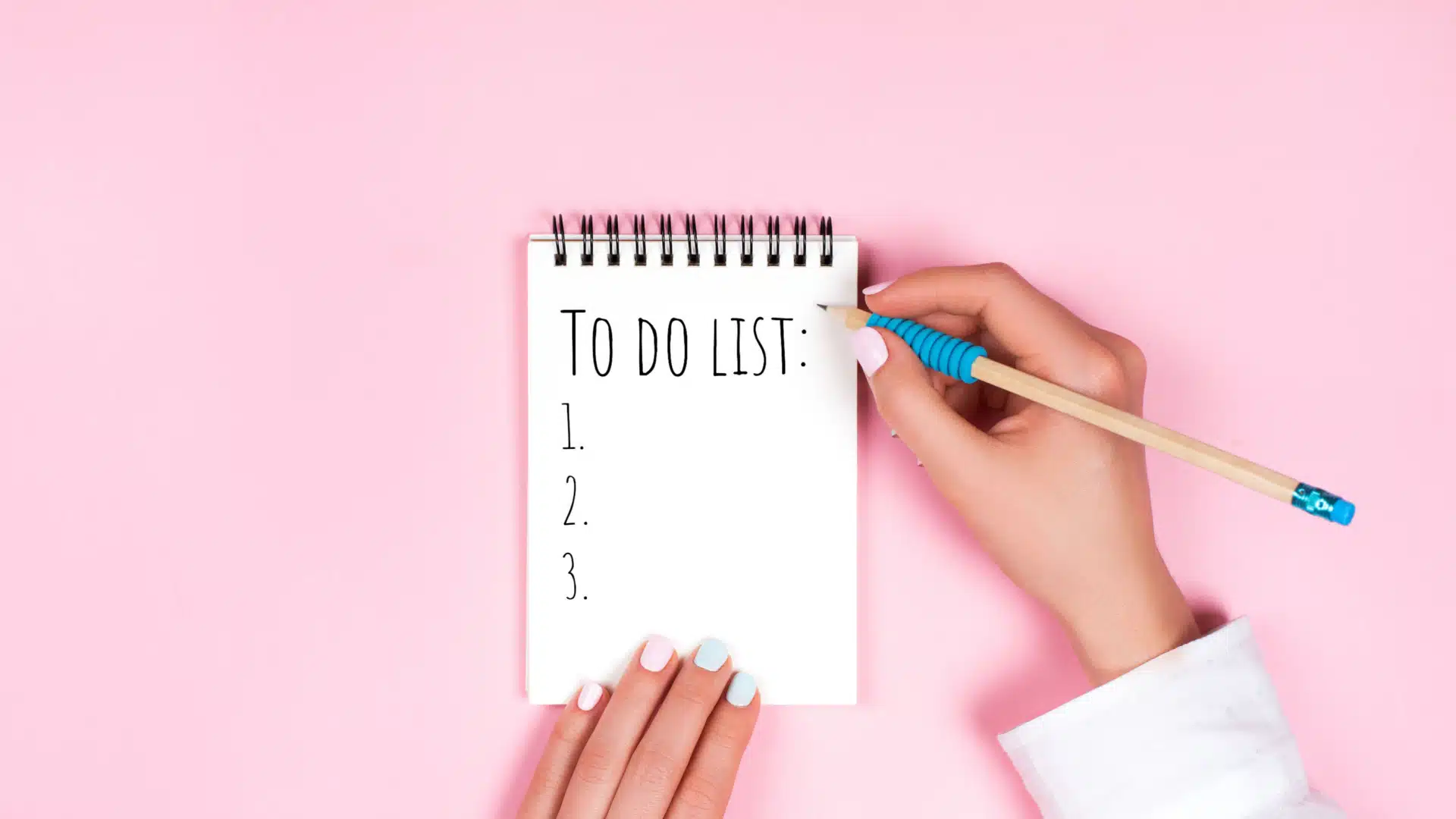 maini care scriu o lista de sarcini pe un fundal roz
