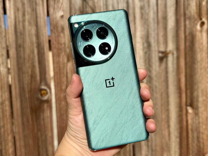 OnePlus 12 in Flowy Emerald tinut in mana in lumina soarelui.