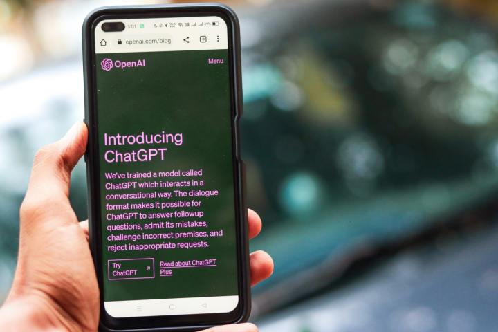 Mana unei persoane care tine un smartphone. Smartphone-ul afiseaza site-ul web pentru IA generativa ChatGPT.