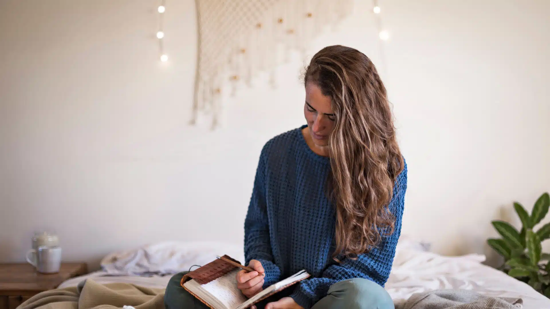 femeie care sta in patul ei scriind intr-un jurnal